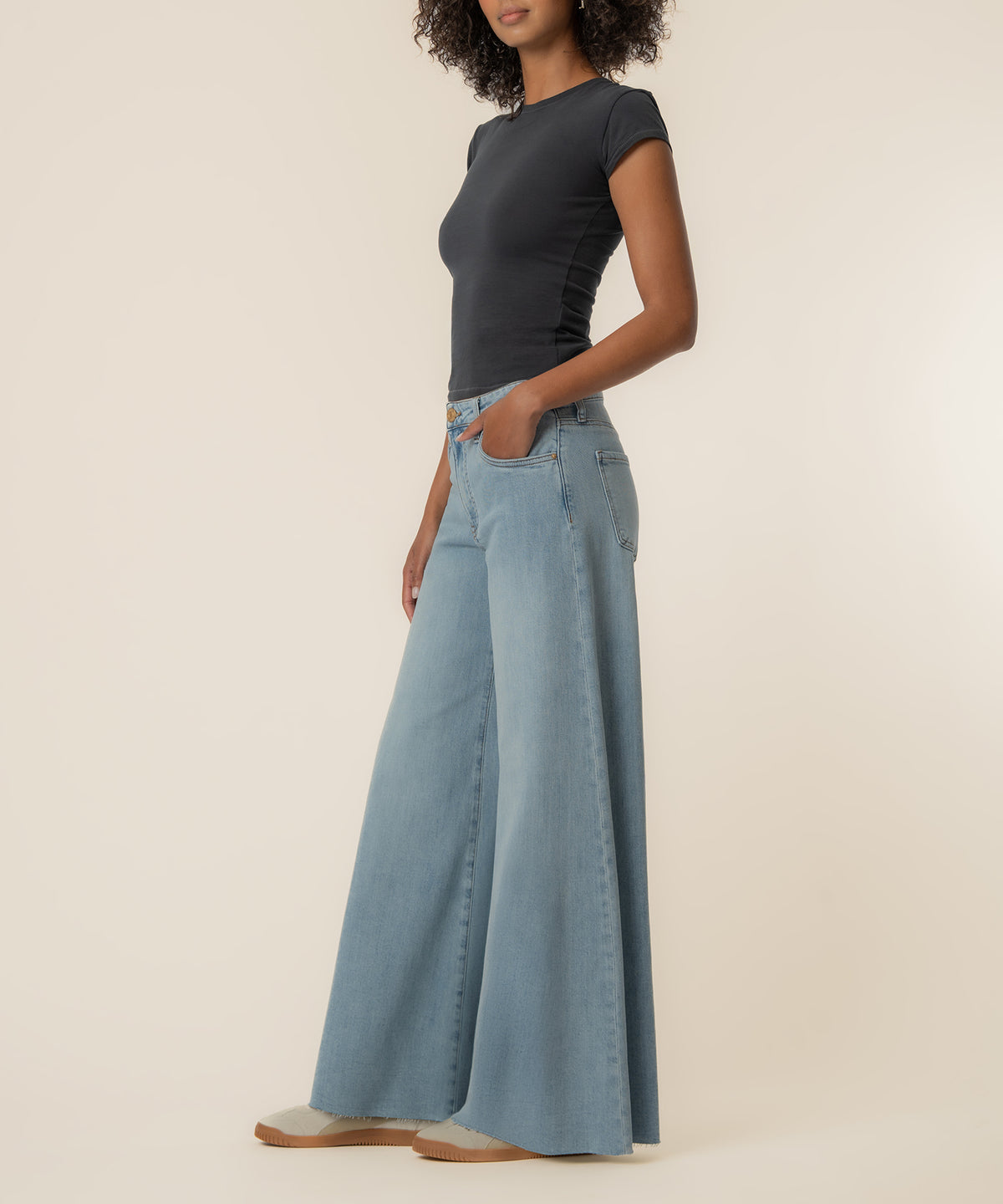 Woman wearing black short-sleeve top and light blue high-rise wide-leg jeans with brown sole shoes.