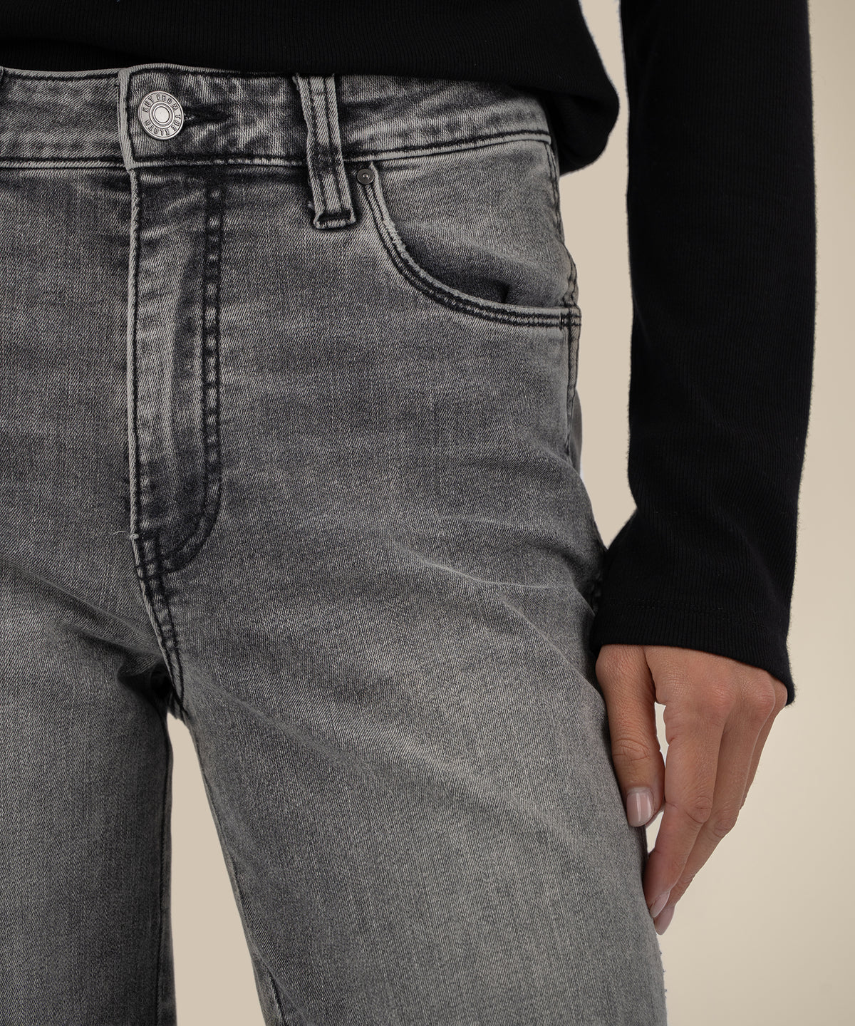 Gray high-rise straight-leg jeans with button fly and visible stitching detail worn with black long-sleeve top.