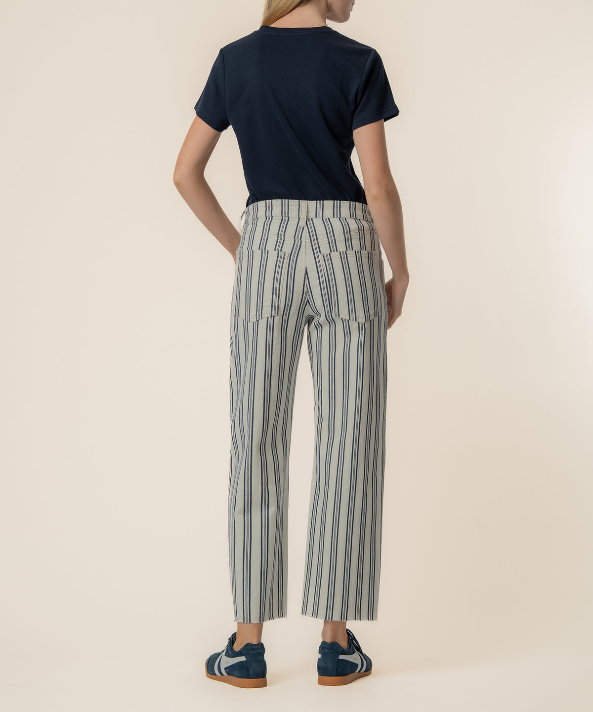 Woman wearing navy t-shirt and navy/ivory striped high-rise wide-leg twill pants with sneakers, shown from back.
