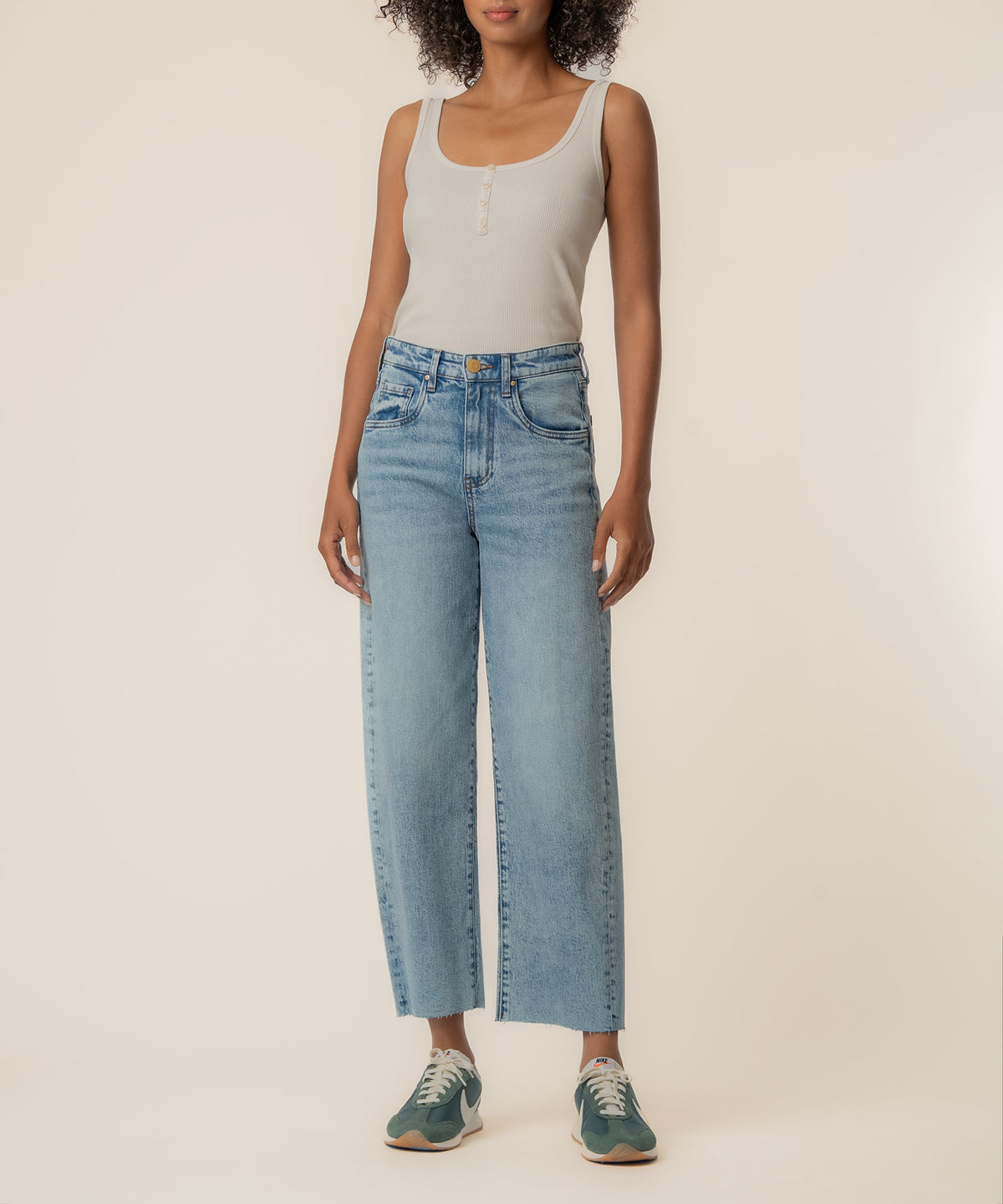 Light-wash high-rise wide-leg jeans with a cream tank top and sneakers.