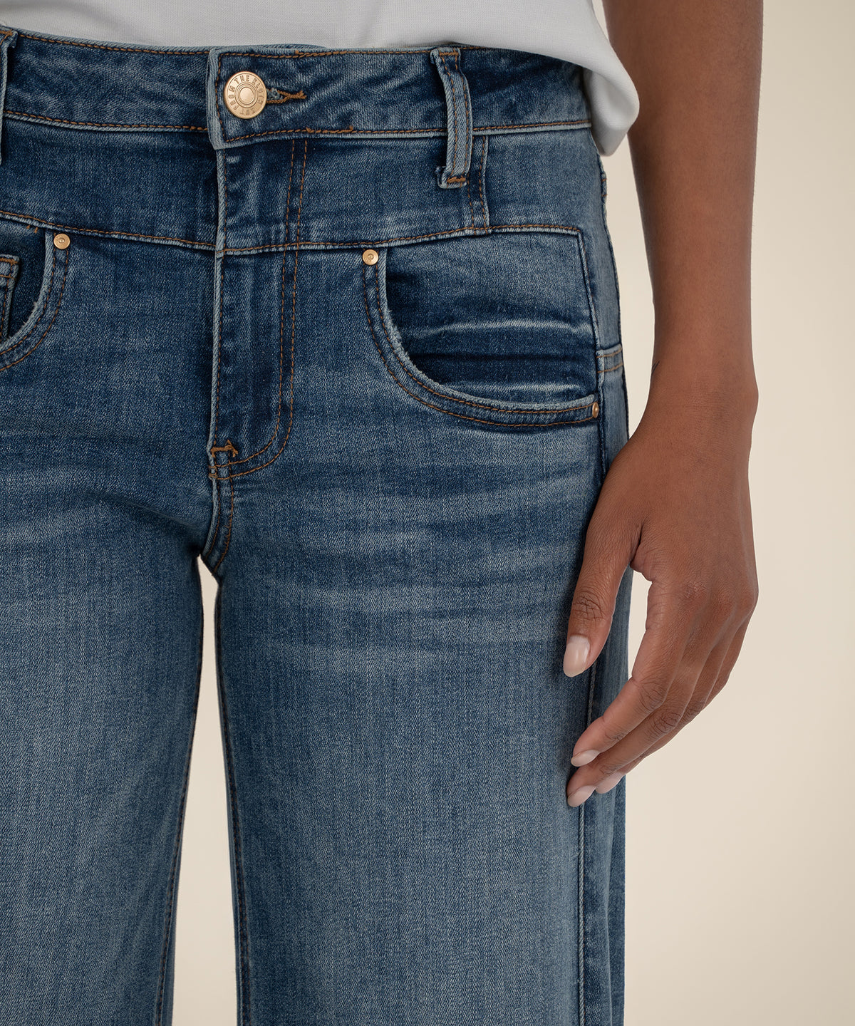 High-rise wide-leg jeans in medium blue denim with copper button and rivets, shown at waistband and pocket detail.