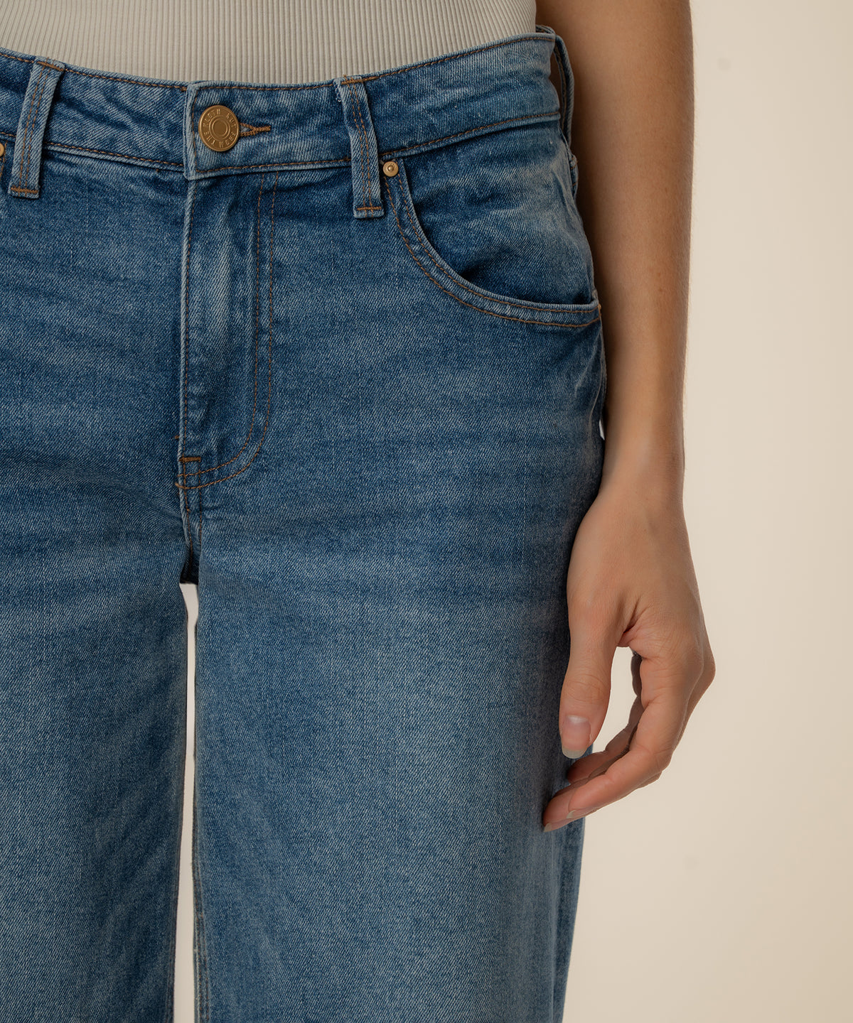Medium wash straight leg jeans with low rise waistband and brass button closure.