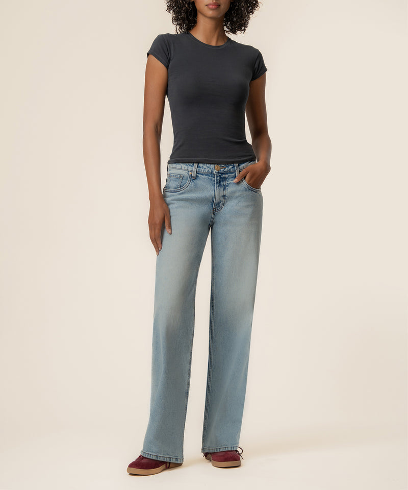 Light-wash baggy straight-leg jeans with low rise, styled with black short-sleeve shirt.