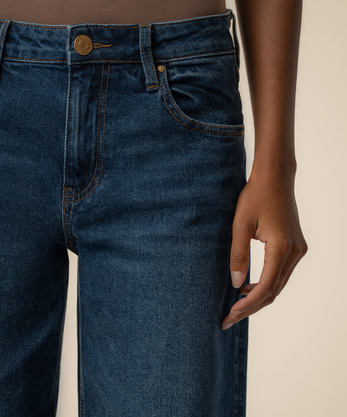 Dark blue baggy low-rise straight leg jeans with bronze button and stitching detail at waistband.