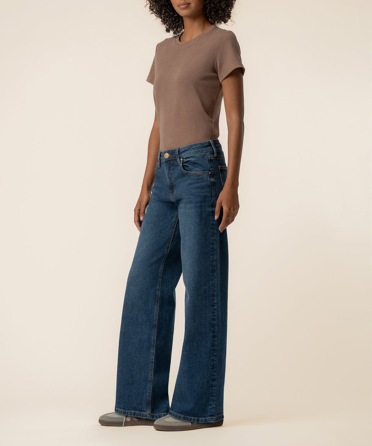 Woman wearing a taupe short-sleeve tee and blue baggy low-rise straight-leg jeans with a medium wash.