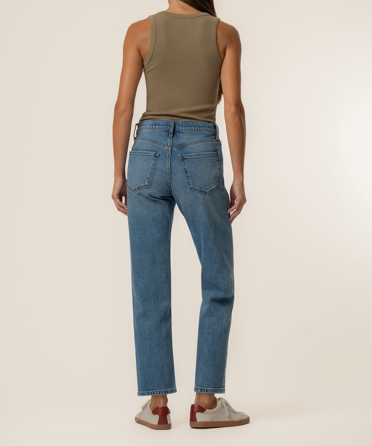 Woman wearing high-rise blue jeans with straight legs and ankle length, styled with a tan sleeveless tank top.