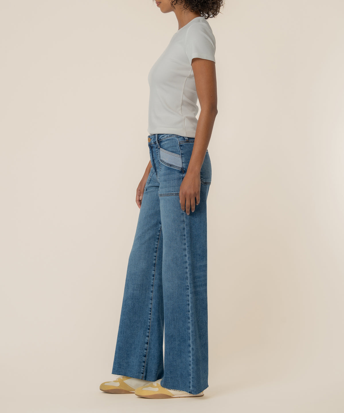 Woman wearing white short-sleeve t-shirt and blue denim high-rise wide-leg jeans in medium wash.