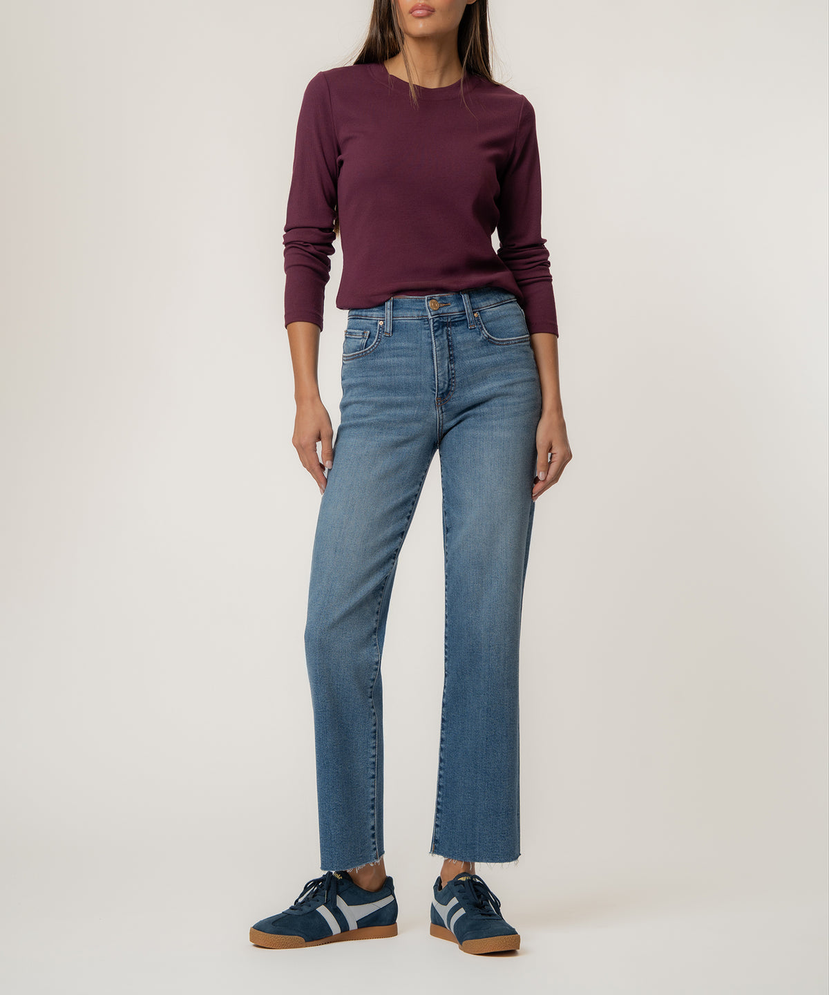 Light blue straight leg jeans with high rise waistband, shown with burgundy long-sleeve top and navy sneakers.