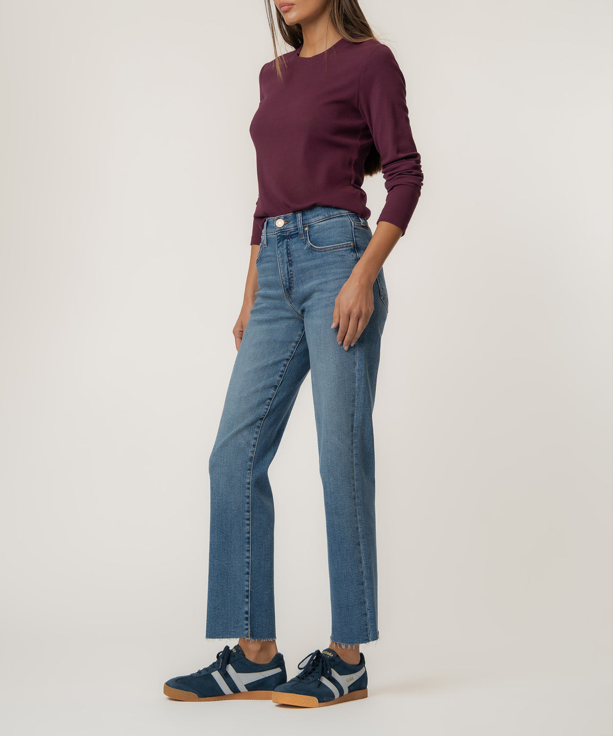 Woman wearing medium-wash straight-leg jeans with high waistband and burgundy long-sleeve top.