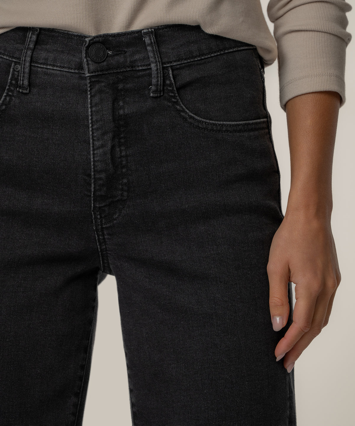 Black high-rise straight-leg jeans with visible stitching, worn with a beige ribbed sweater.