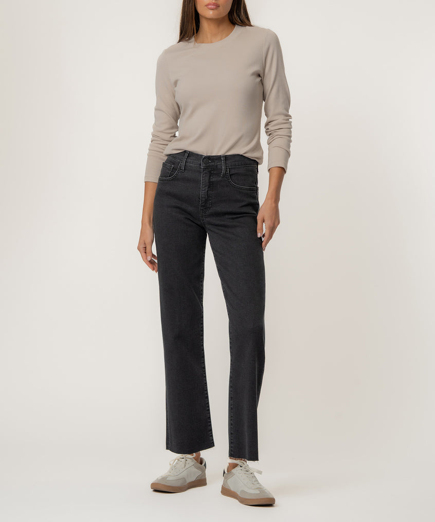 Woman wearing beige long-sleeve top and black high-rise straight-leg jeans with white sneakers.