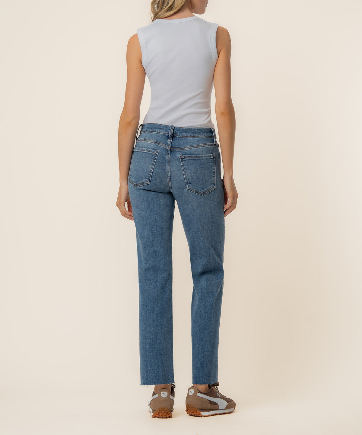 Woman wearing light blue sleeveless tank top and medium wash high-rise straight leg jeans, shown from behind.