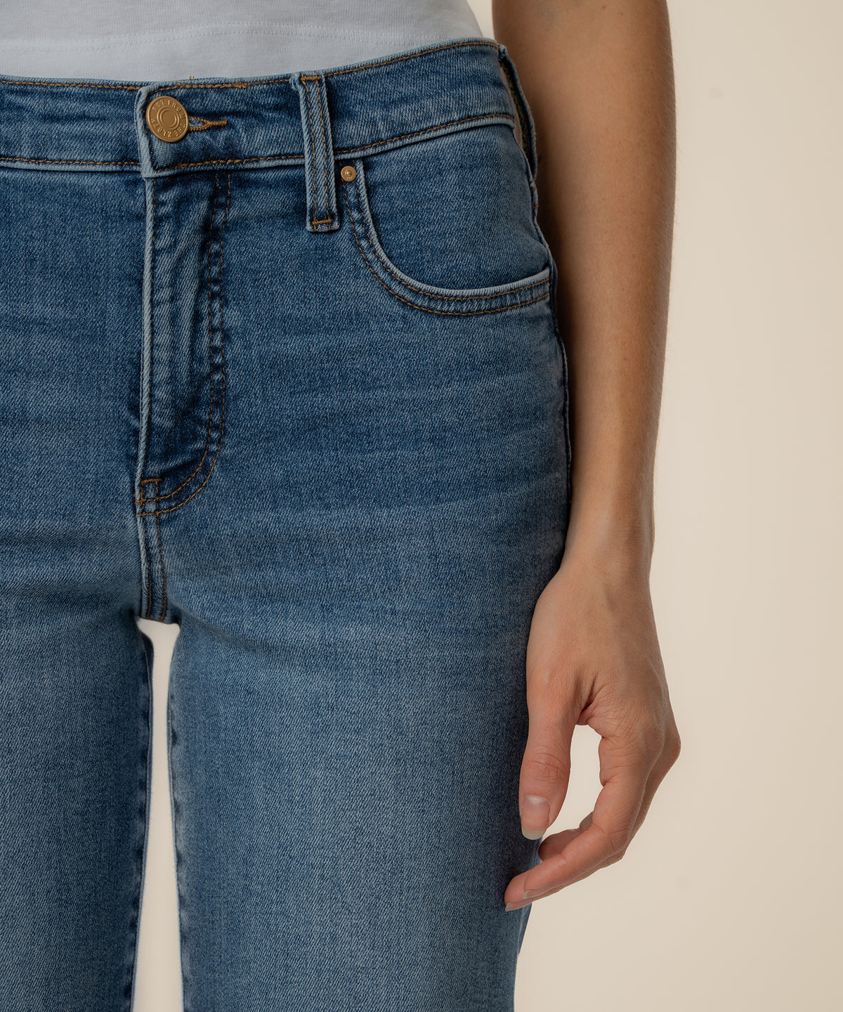 High-rise medium-wash straight leg jeans with gold button and visible stitching detail on waistband and pockets.