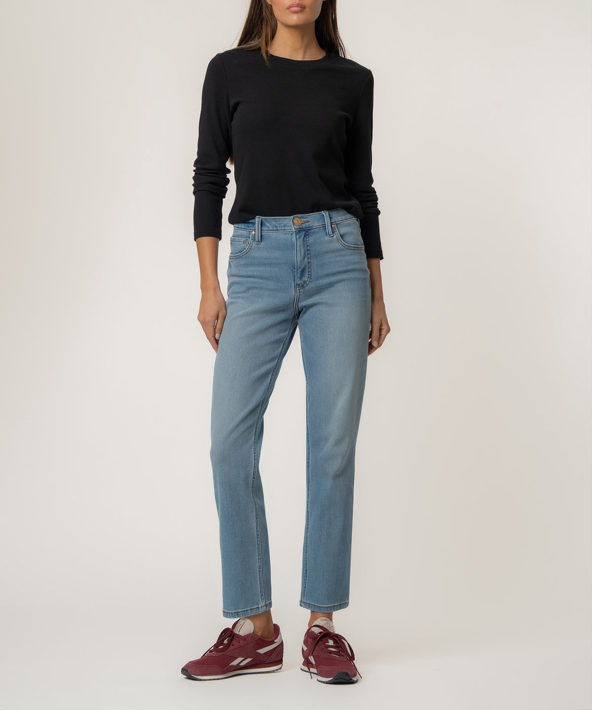 Woman wearing light blue straight-leg jeans with high rise waistband and black long-sleeve top.
