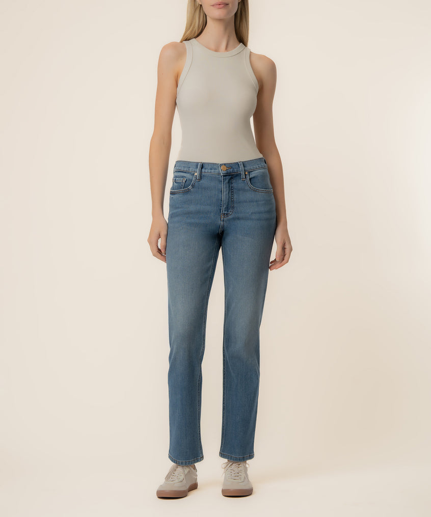 Woman wearing light beige sleeveless tank top and blue high-rise straight-leg jeans with a medium wash.