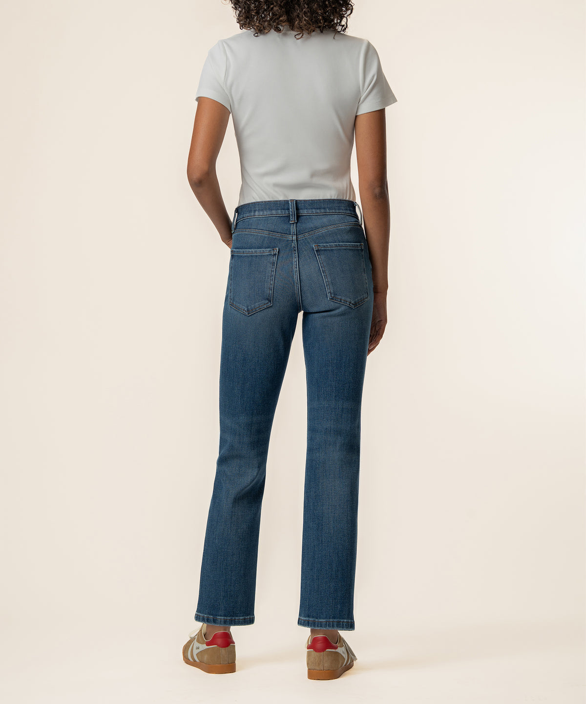 Woman wearing high-rise straight leg jeans in medium blue wash with white t-shirt, shown from back.