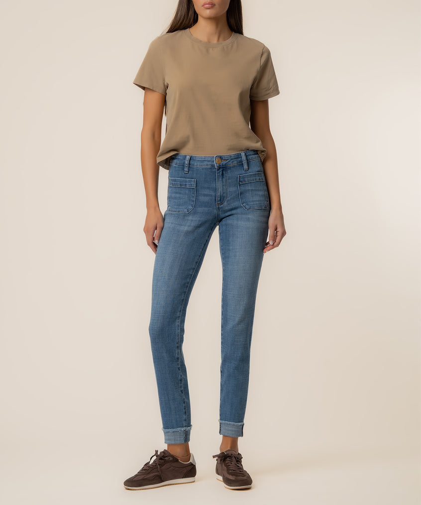 Woman wearing beige t-shirt and blue straight-leg jeans with cuffed ankles.