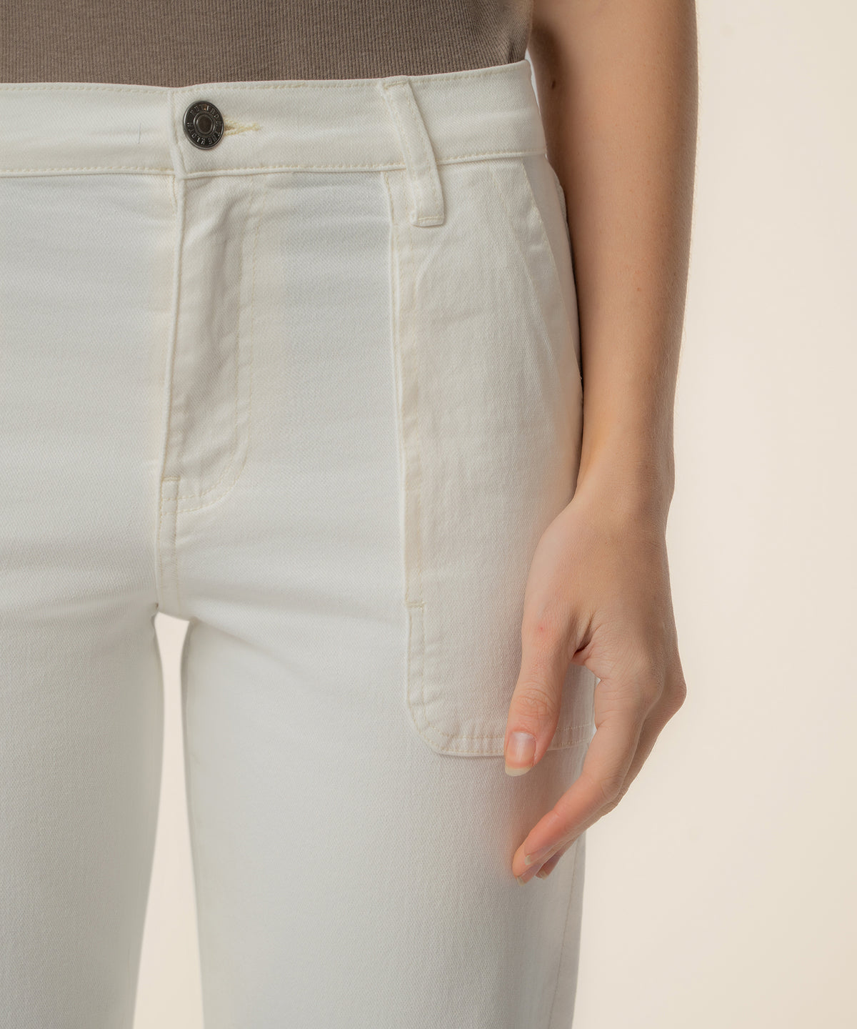Ivory high-rise straight leg jeans with button closure and visible seams, worn at the waist.