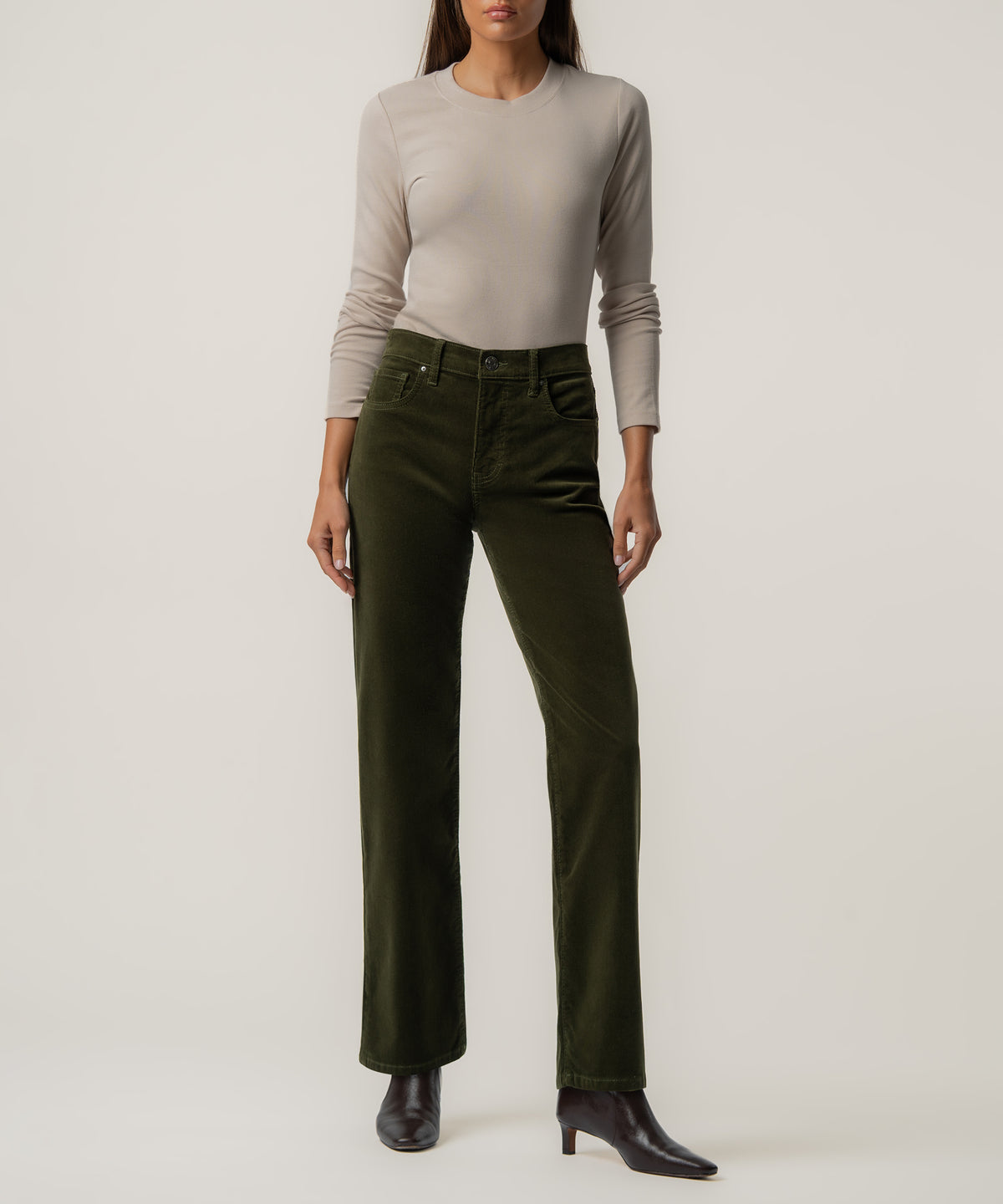 Woman wearing tuscan olive corduroy high-rise straight pants with a beige long-sleeve shirt and black ankle boots.