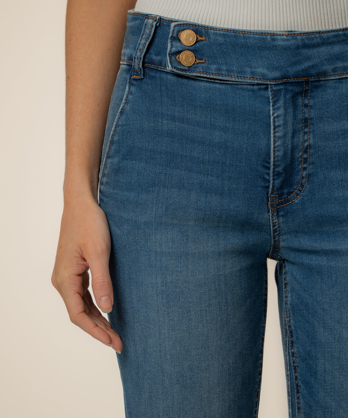 High-rise medium wash denim flare jeans with gold buttons and visible seaming detail.