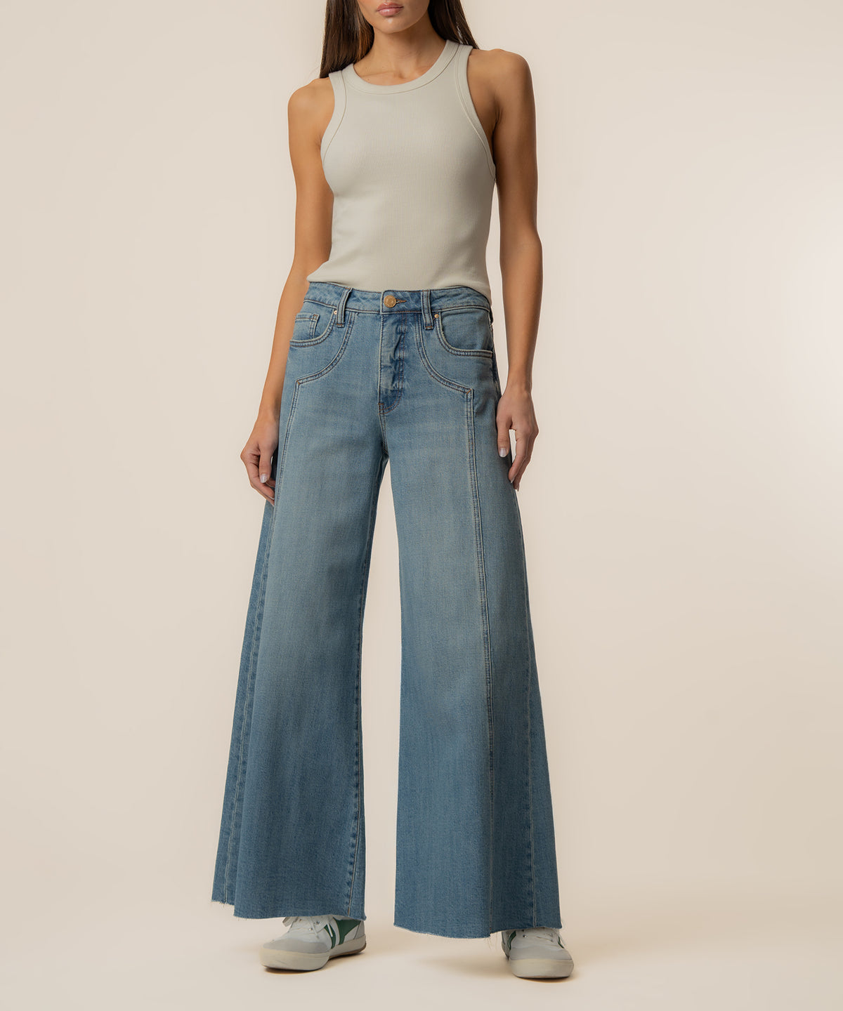 Woman wearing light gray sleeveless tank top with light blue high-rise wide-leg jeans in medium wash.