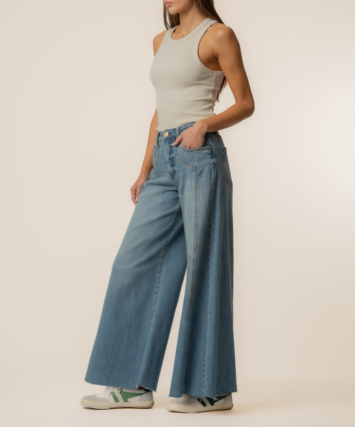 Woman wearing light gray sleeveless tank top and high-rise wide-leg medium wash denim jeans.