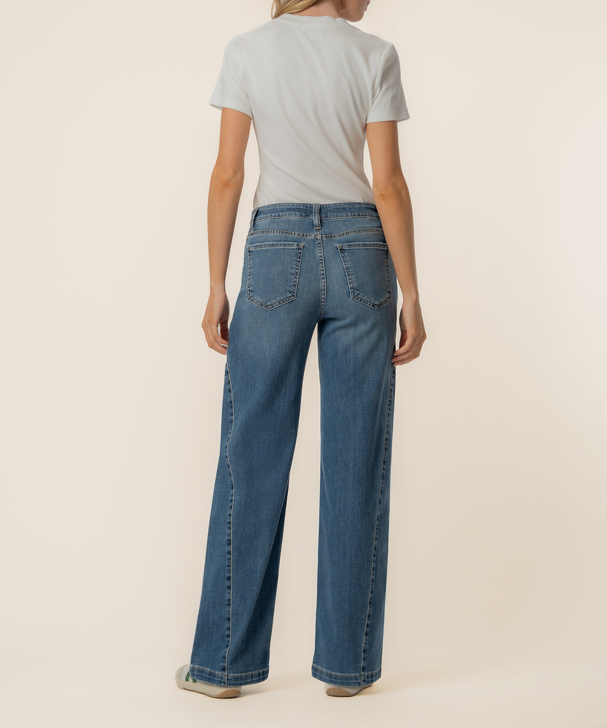 Woman wearing light gray t-shirt and medium wash wide-leg jeans with high rise and straight leg silhouette, shown from back.