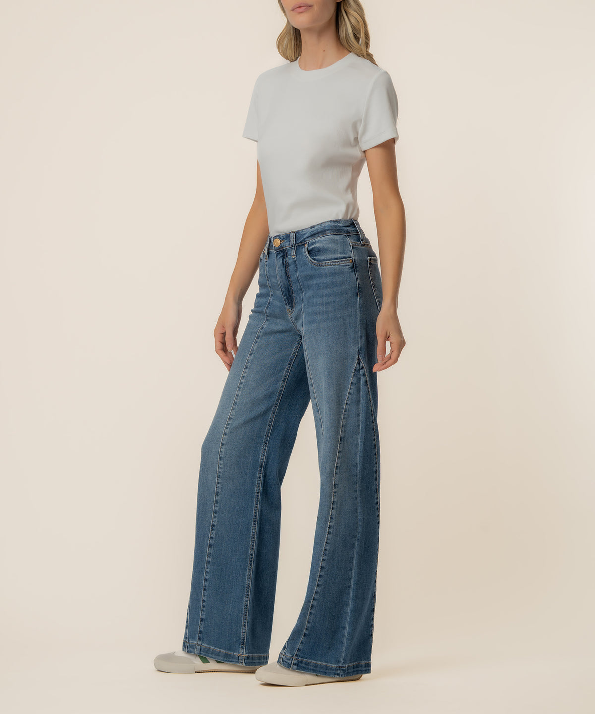Woman wearing light gray t-shirt and high-rise wide-leg blue jeans with straight silhouette.