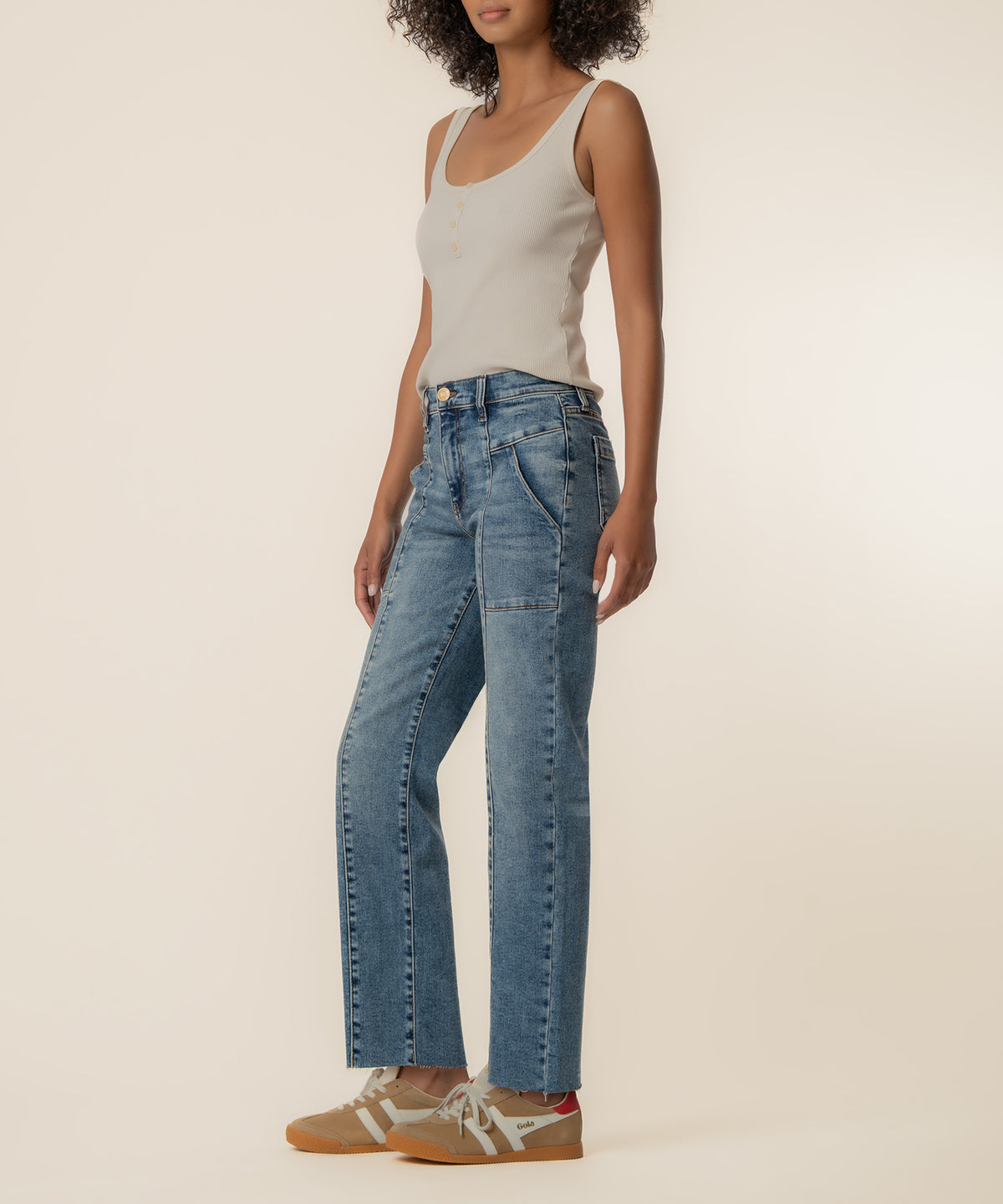Woman wearing light blue straight-leg jeans with high waistband and cream sleeveless tank top.