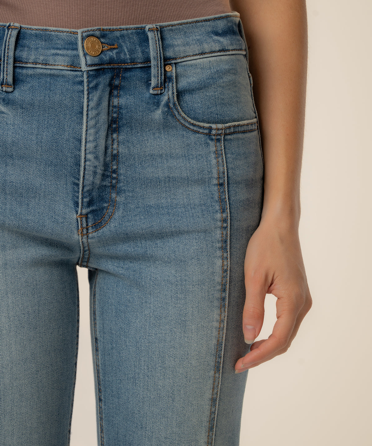 High-rise straight leg jeans in light blue wash with gold button and visible stitching detail.