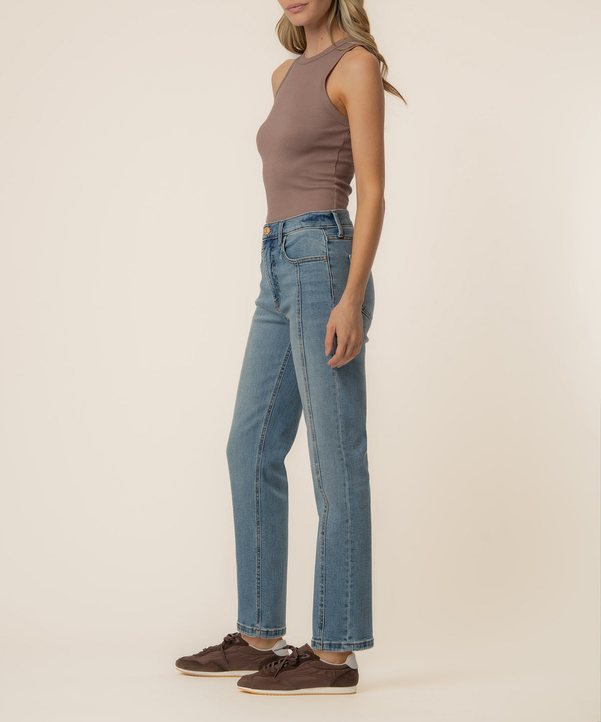 Woman wearing a taupe sleeveless tank top and light blue straight-leg jeans with a high rise waistband.