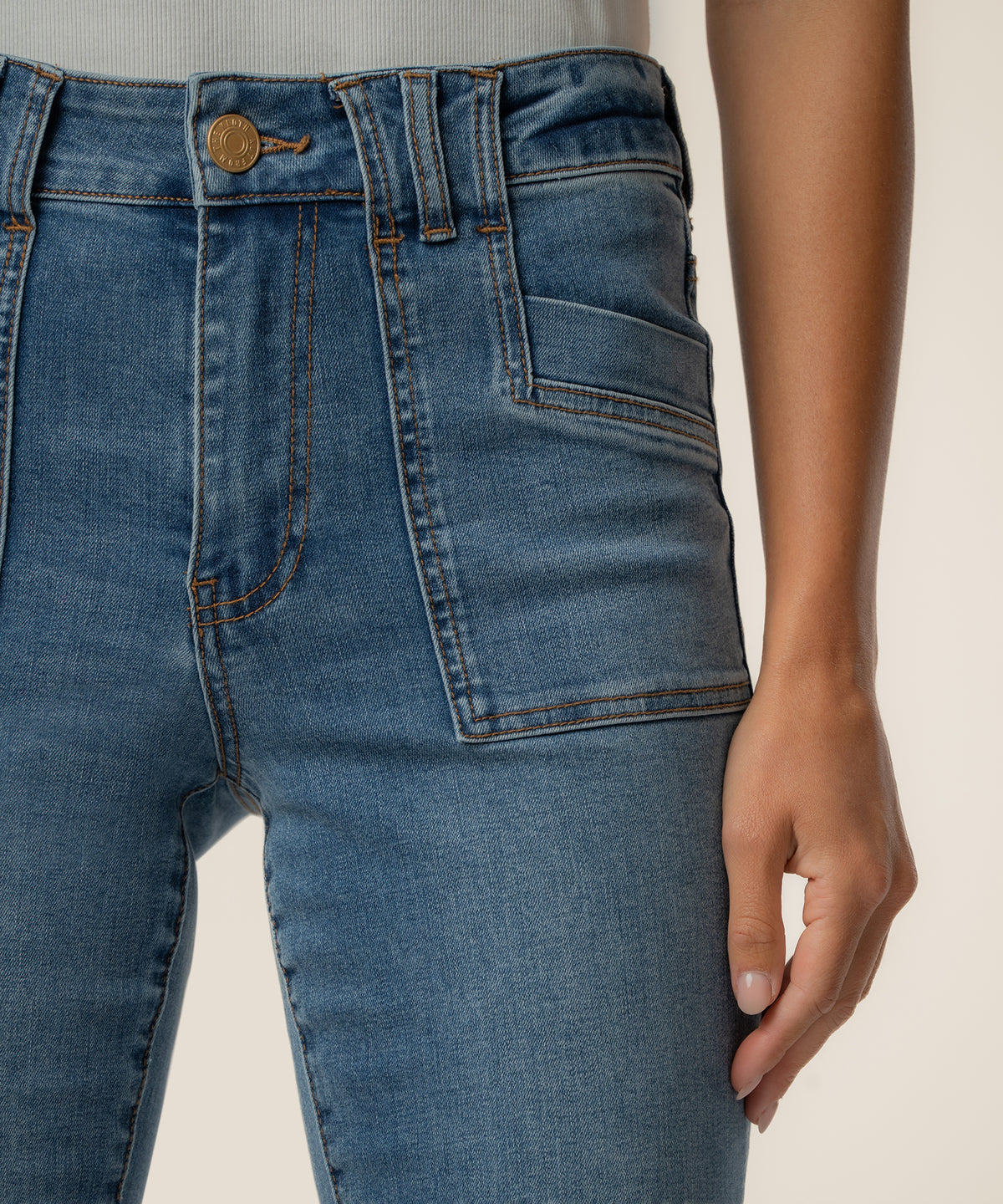 High-rise flare jeans in light blue wash with gold button, front pockets, and stitching detail.