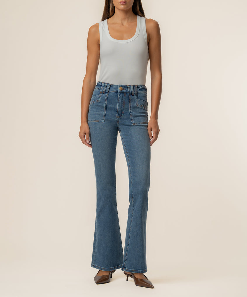 High-rise medium wash flare jeans with patch pockets and a tapered waistband, styled with a white sleeveless tank top.