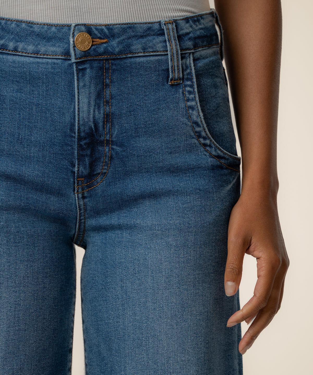High-rise wide-leg jeans in medium blue denim with button closure and visible stitching detail at waistband.