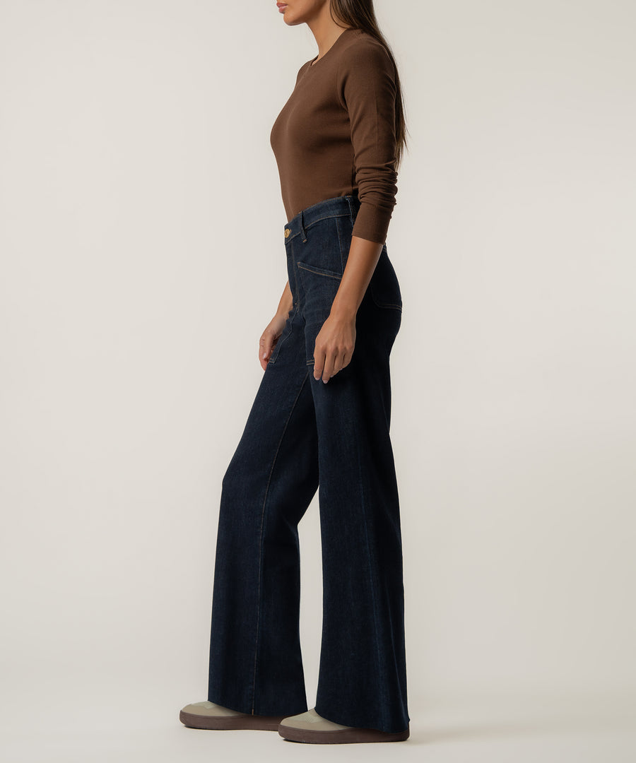 Woman wearing dark indigo straight-leg jeans with a high waistband and brown long-sleeved top.