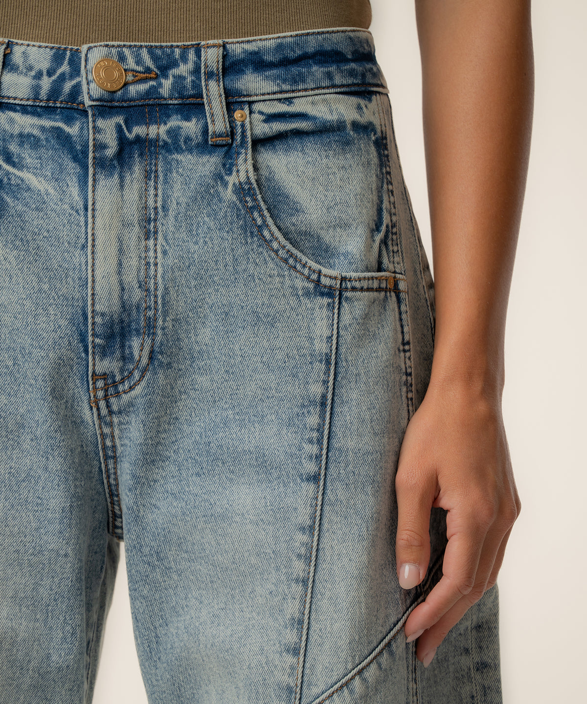 Light-wash high-rise jeans with curved barrel leg silhouette and brass button closure.