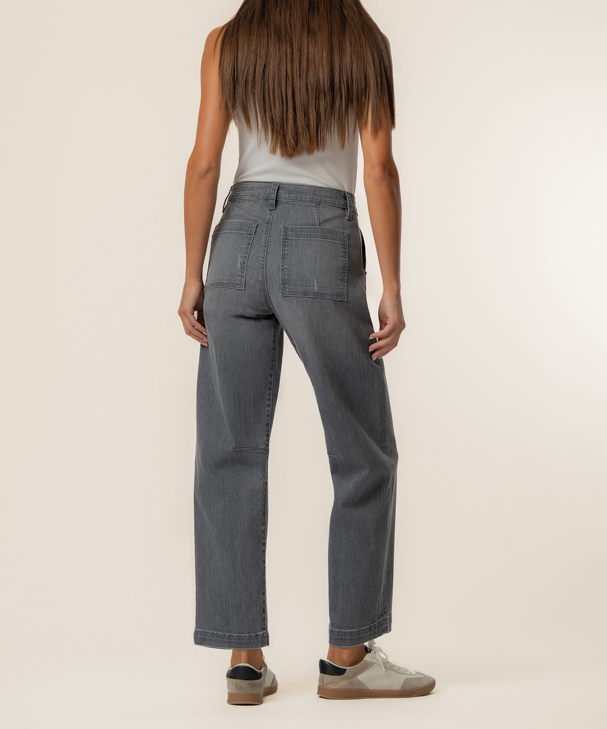 Woman wearing high-rise gray relaxed leg jeans with straight ankle length and visible back pockets, paired with a white tank 