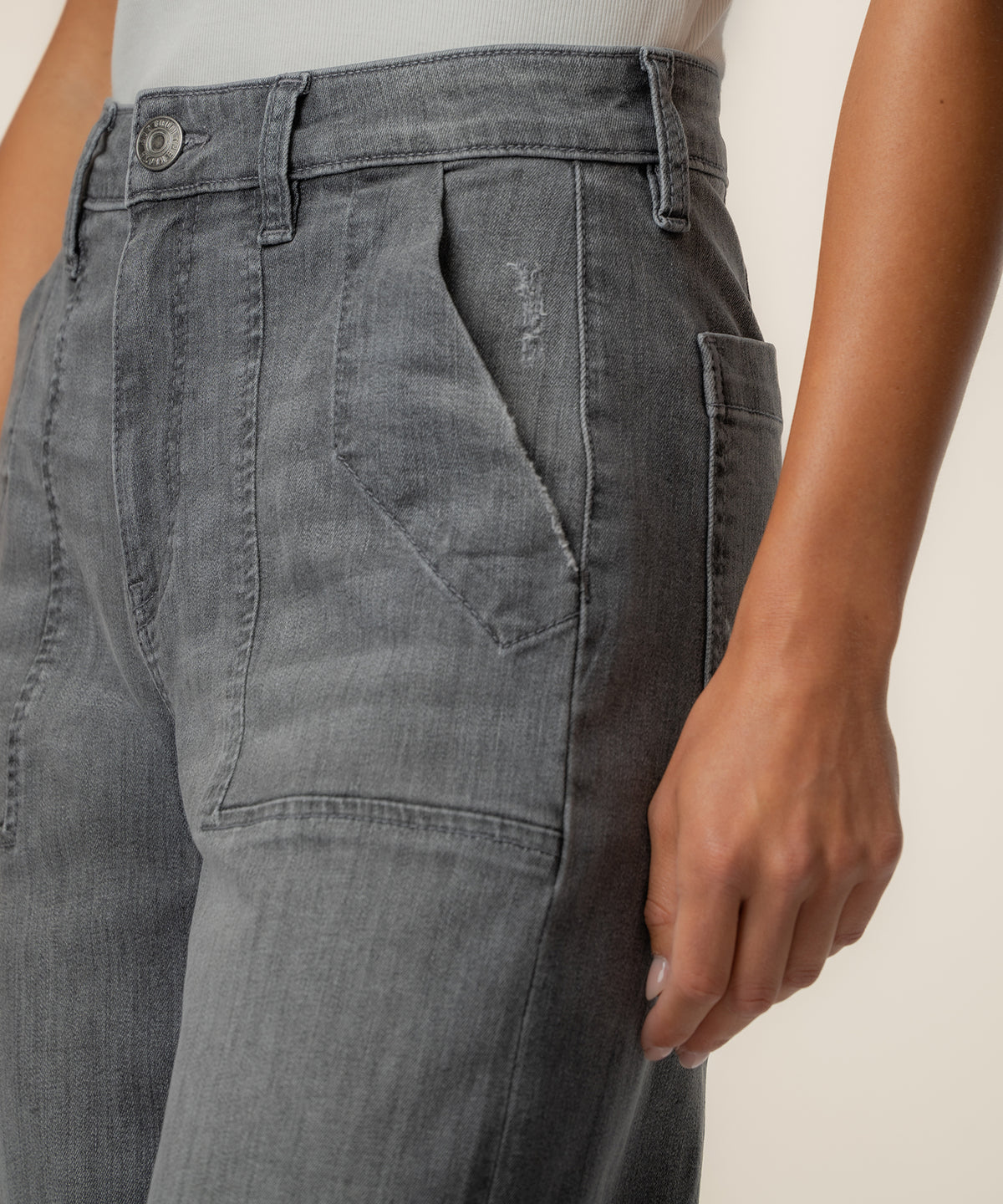 Gray high-rise relaxed-fit jeans with front pockets and button closure, shown on model wearing cream top.
