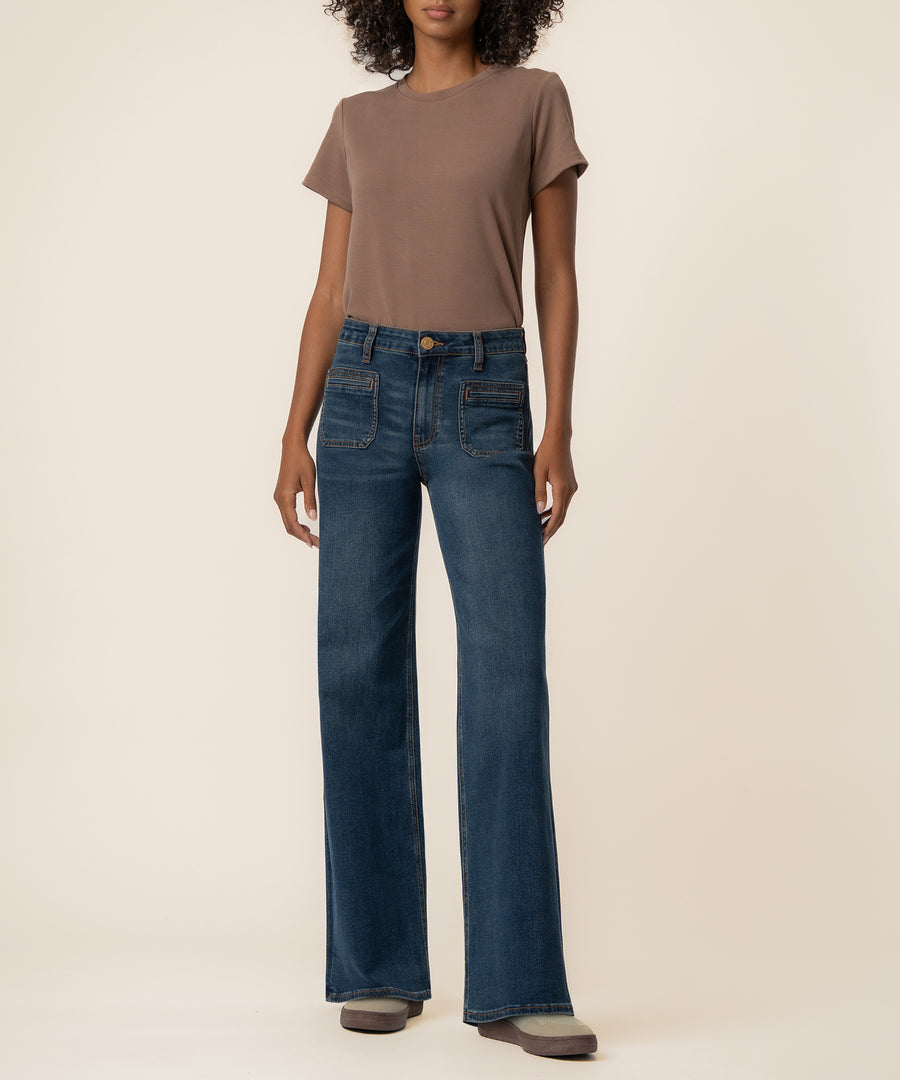 Woman wearing taupe short-sleeve t-shirt and dark blue high-rise straight-leg jeans with visible stitching detail.