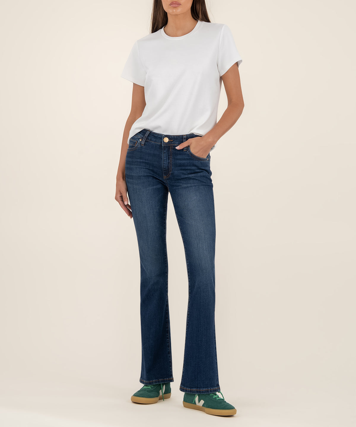 Woman wearing white t-shirt and dark blue mid-rise bootcut jeans with flared legs.