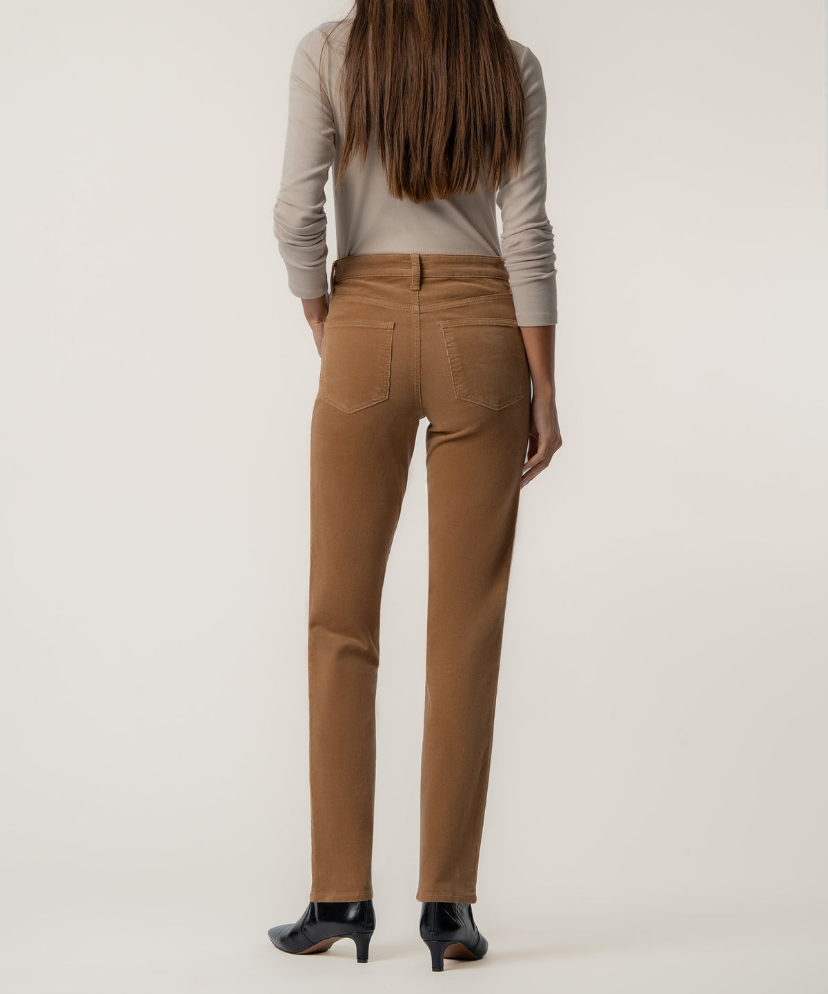 Camel corduroy high-rise mom pant with five-pocket styling shown from back on model wearing cream long-sleeve top.