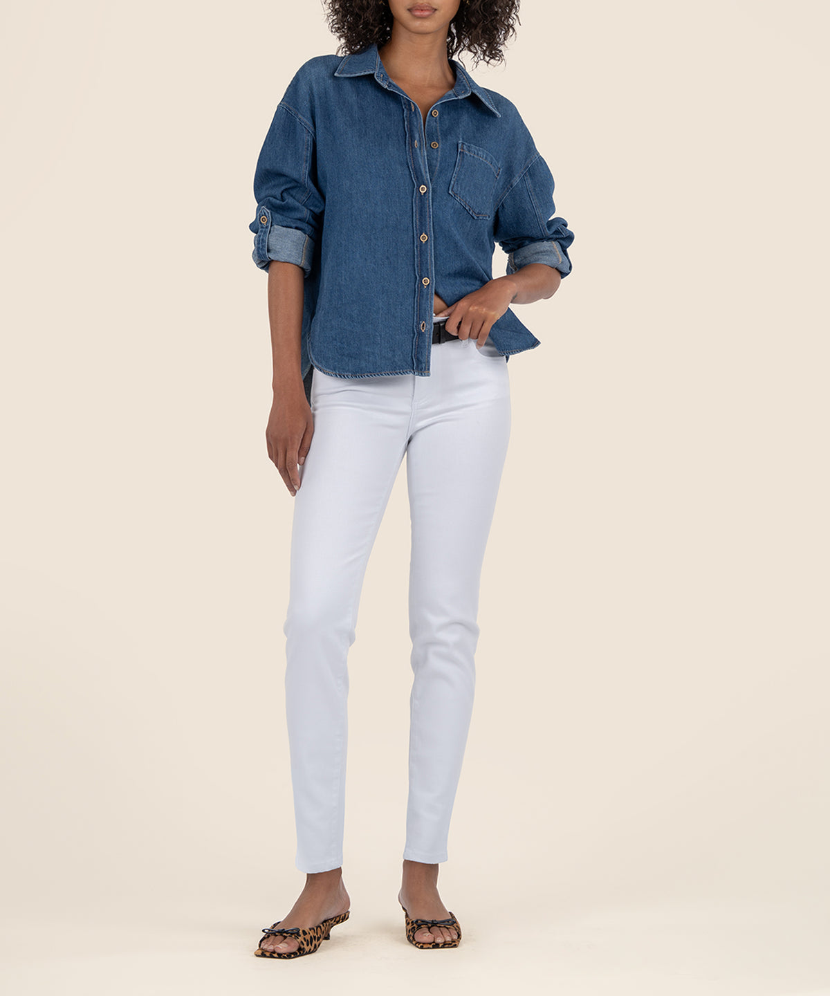 White mid-rise skinny jeans with a tapered leg on a model wearing a blue denim shirt.