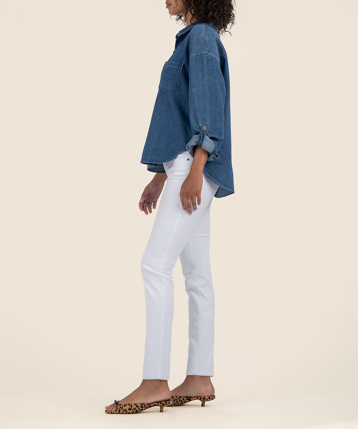 White mid-rise skinny jeans with five-pocket styling shown on model wearing denim shirt.