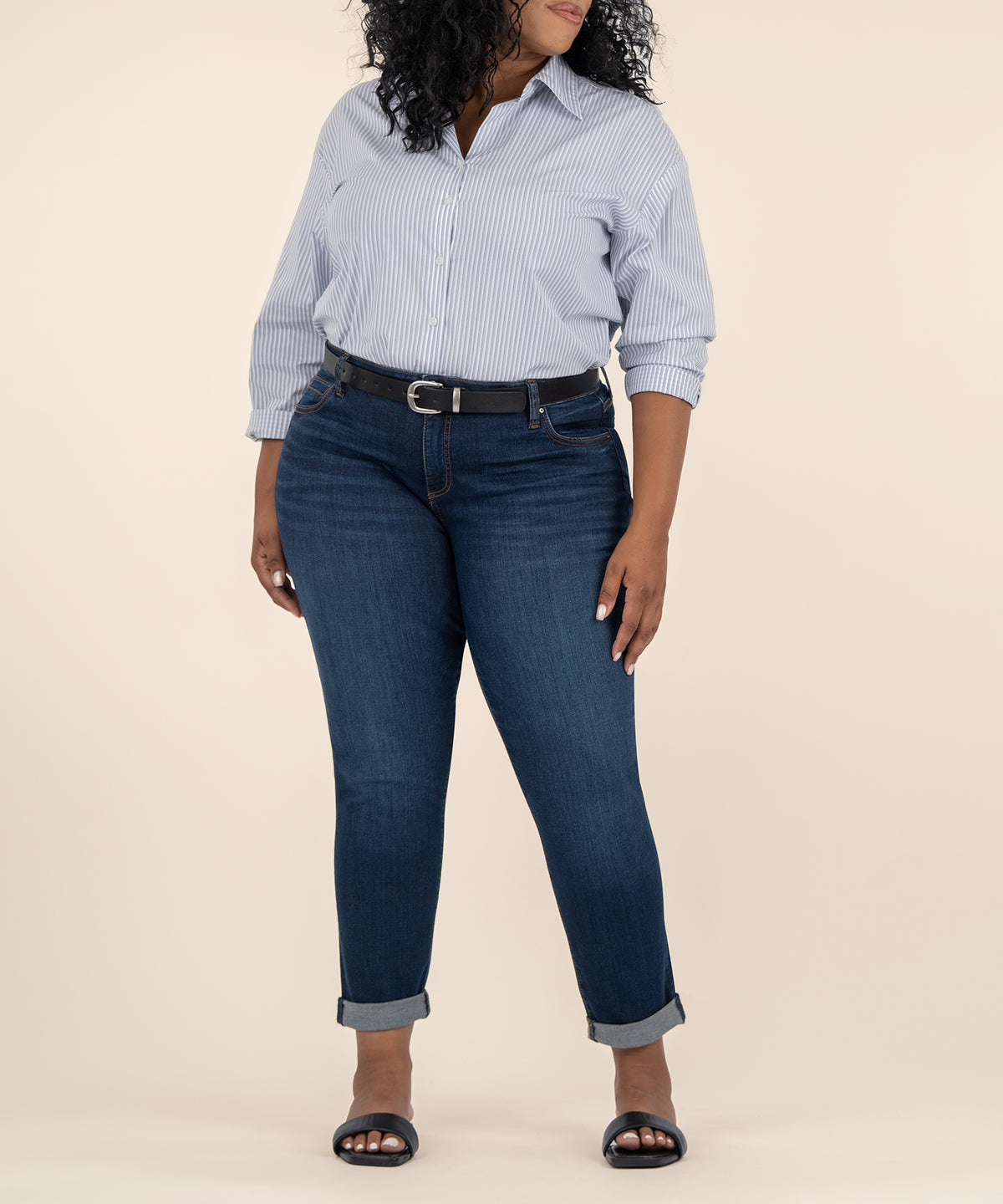 Woman wearing light blue striped button-up shirt and dark blue jeans with rolled cuffs and black belt.