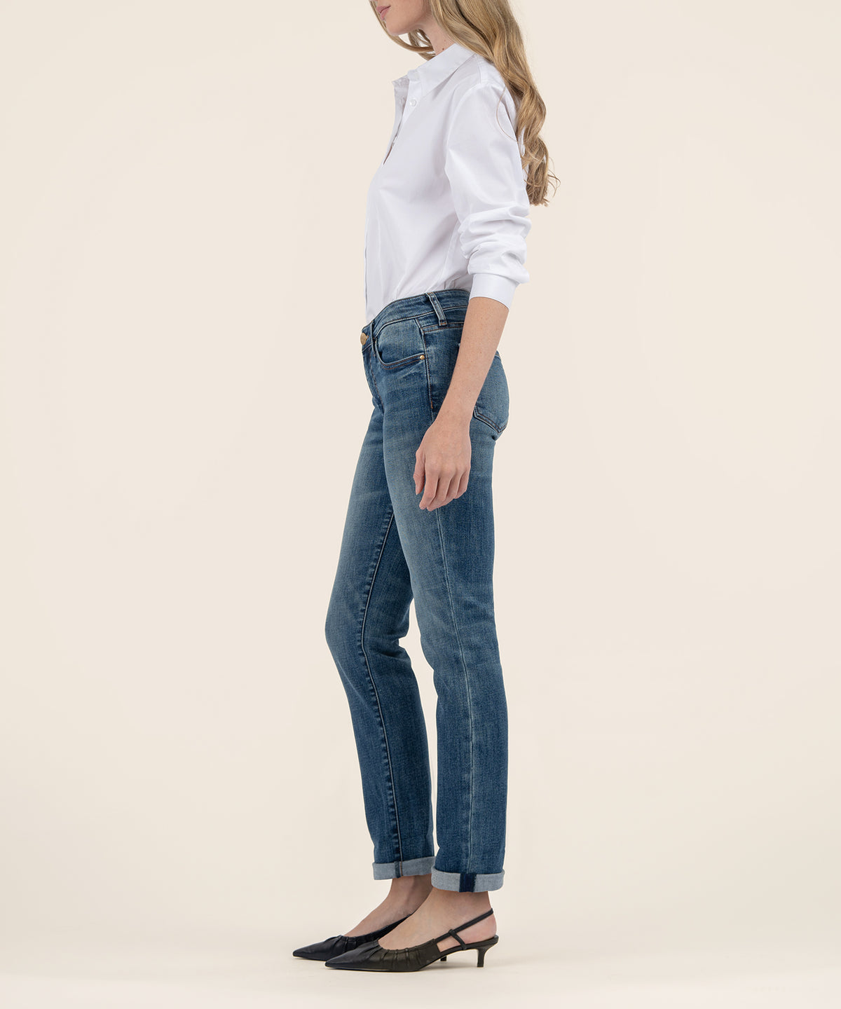 Woman wearing white long-sleeve button-up shirt and blue mid-rise boyfriend jeans with rolled cuffs, styled with black kitten