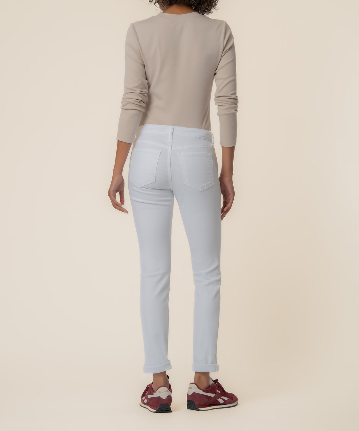 Woman wearing optic white mid-rise boyfriend jeans with five-pocket styling and cropped ankle length, shown from behind.