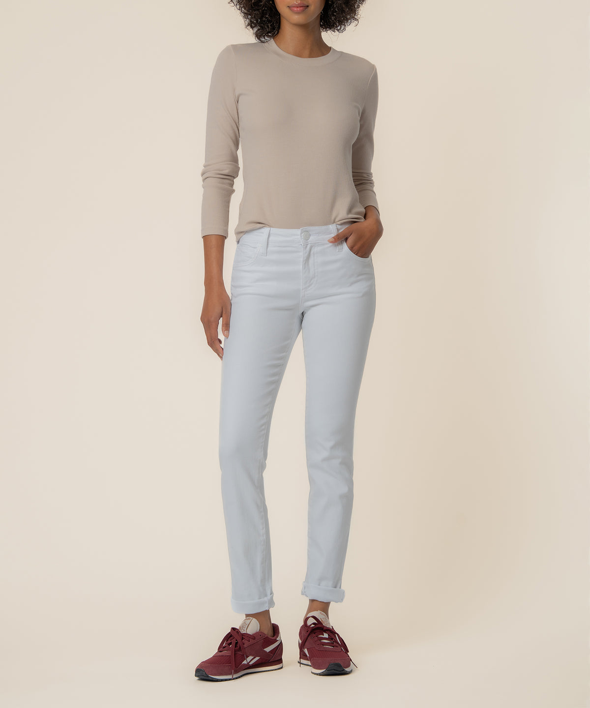 Woman wearing light blue mid-rise boyfriend jeans with cuffed ankles and a beige long-sleeve top.