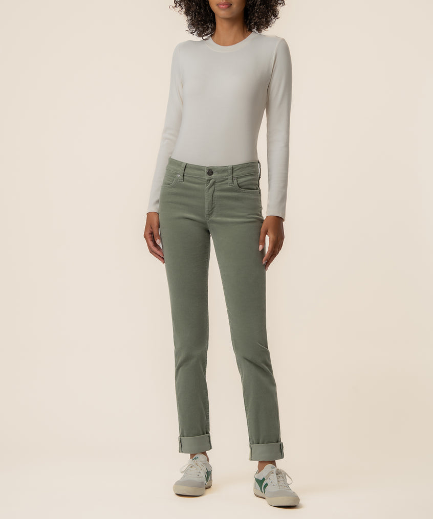 Woman wearing sea star green corduroy mid-rise boyfriend jeans with cuffed ankles and a cream long-sleeve top.