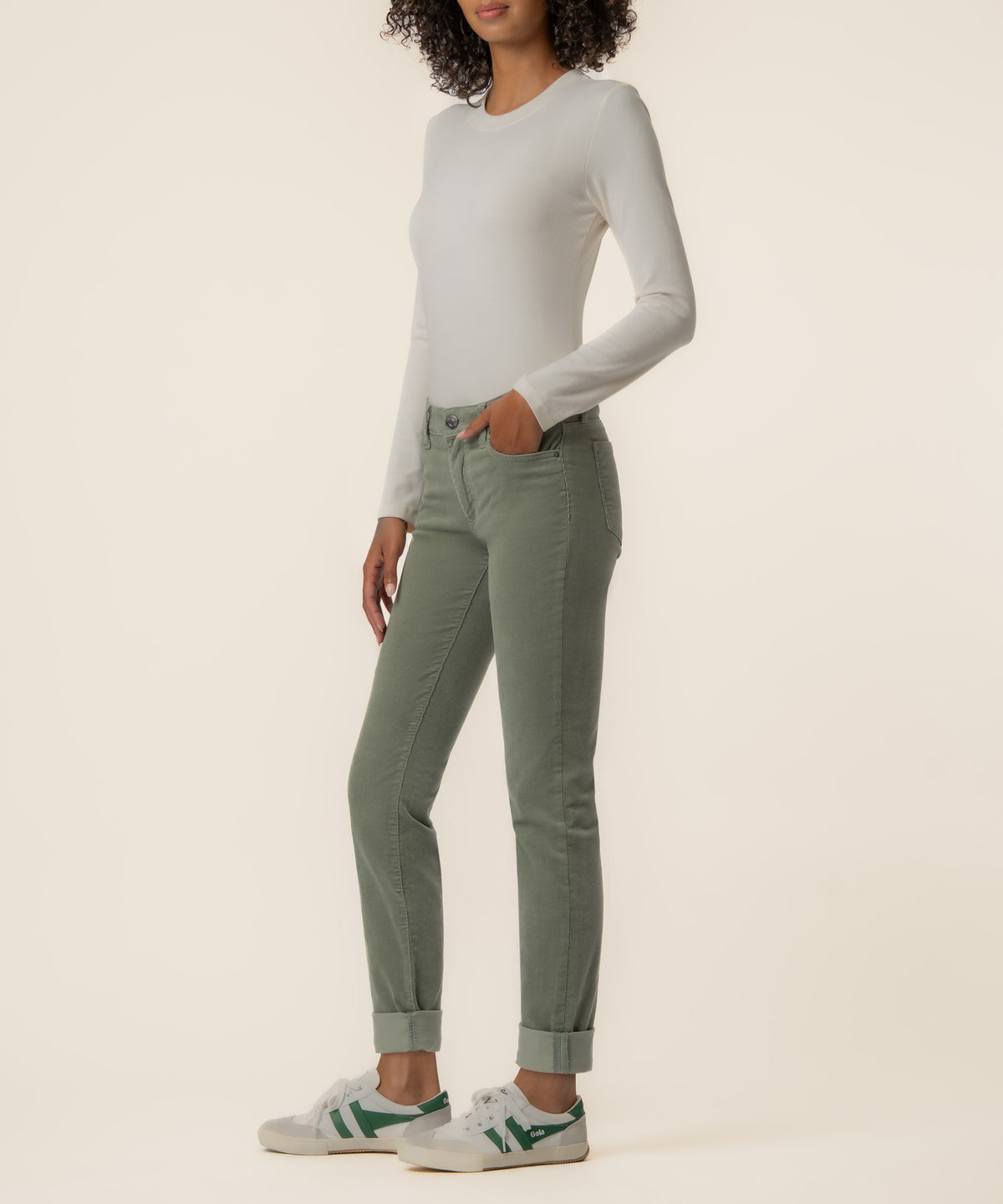 Sea Star green corduroy mid-rise boyfriend jeans with rolled cuffs on model wearing cream long-sleeve top.