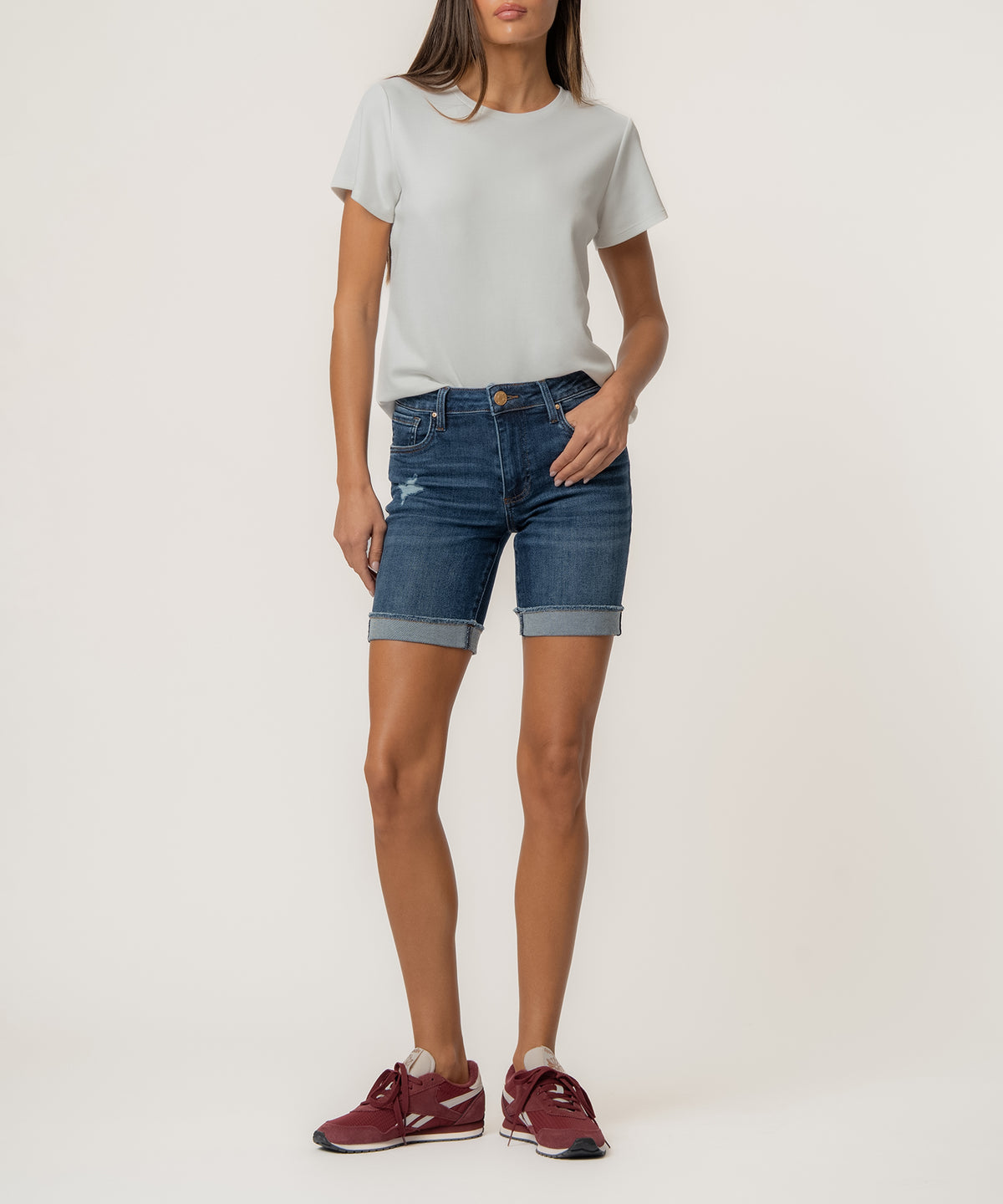 Woman wearing white t-shirt and dark blue denim shorts with rolled cuffs.